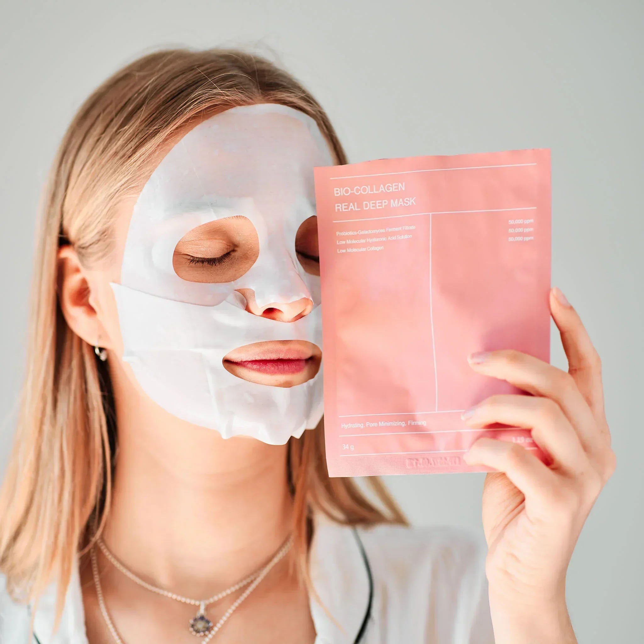 Woman with glowing skin wearing a bio-collagen face mask while holding the product packaging – deep hydration and anti-aging skincare